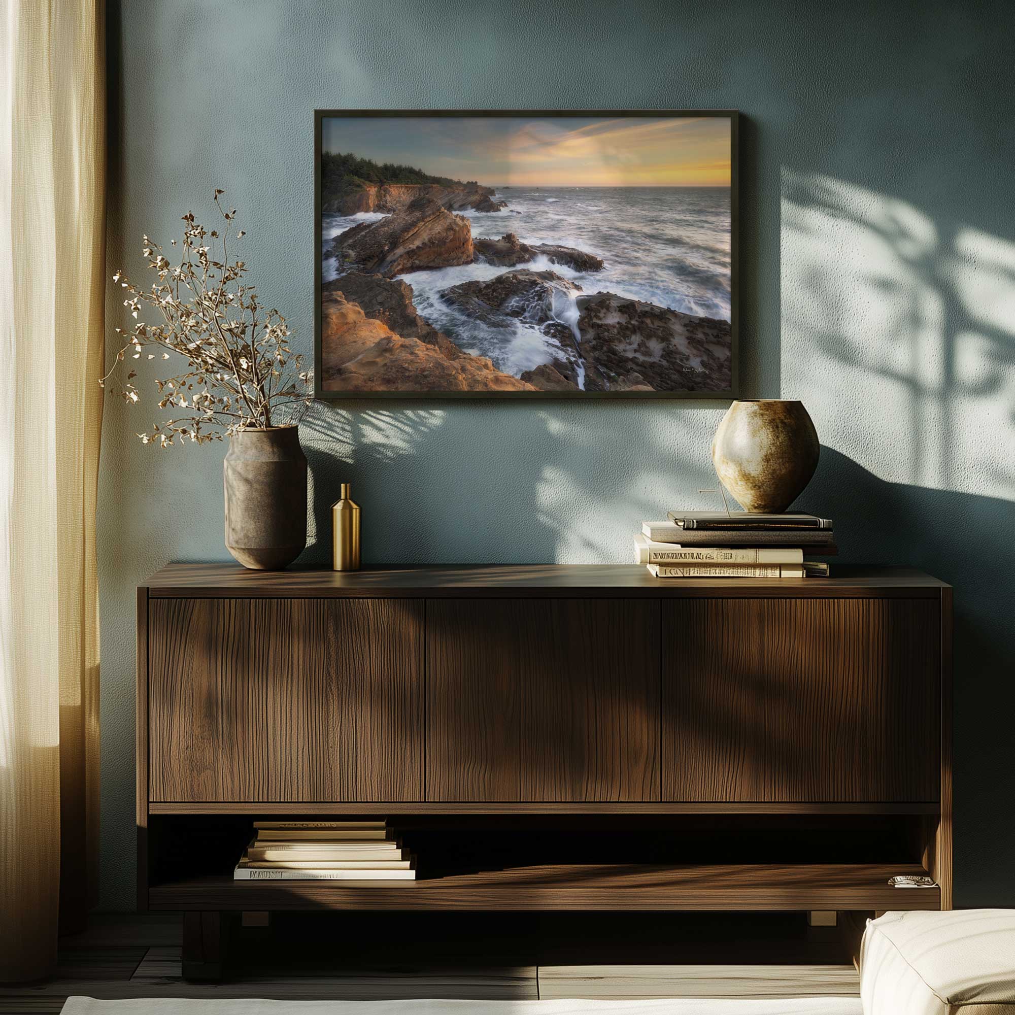 rocky coastline at sunset art print in a black frame hanging above a console table